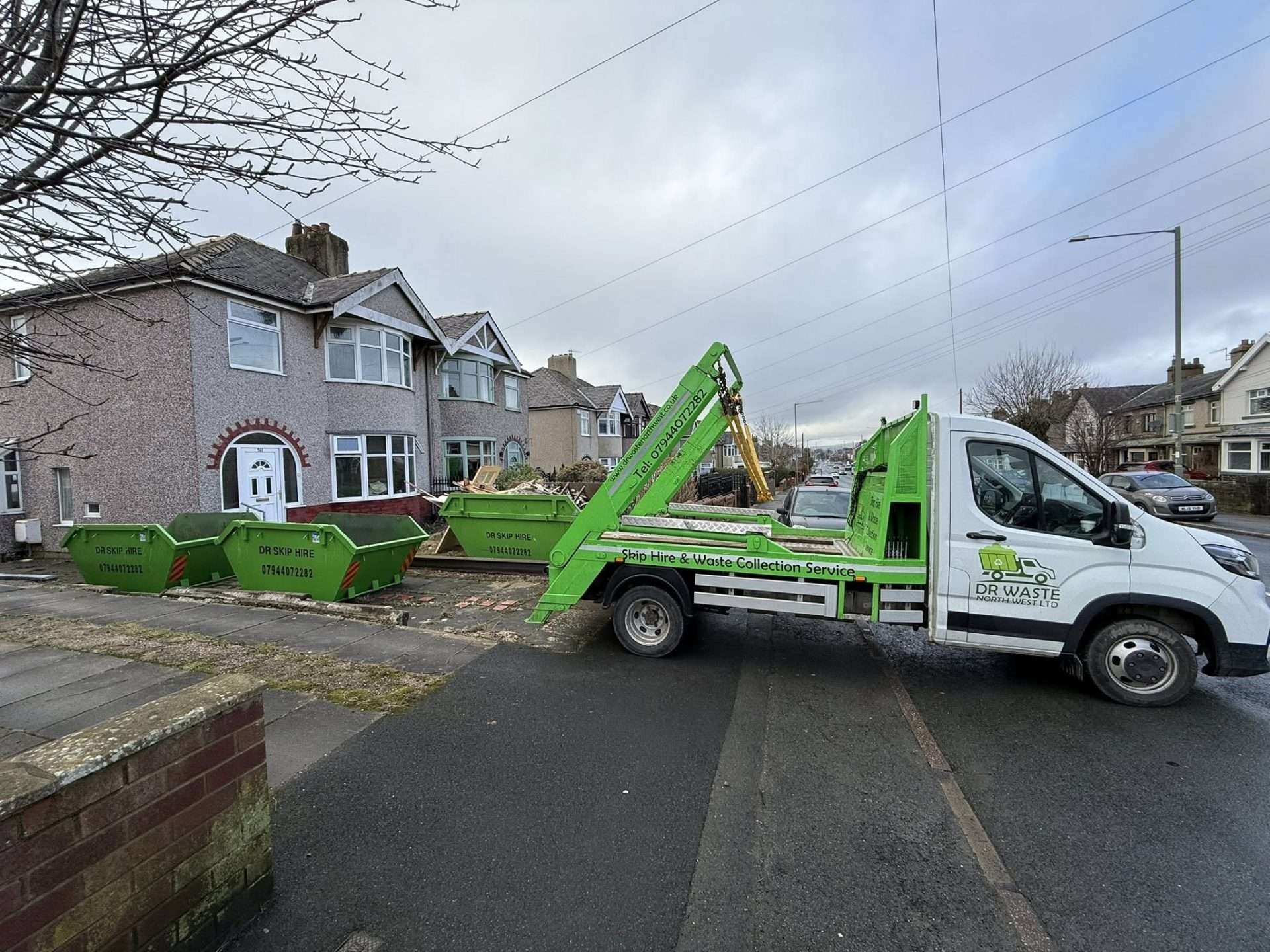 DR Skip Hire lorry dropping skips on a residential street